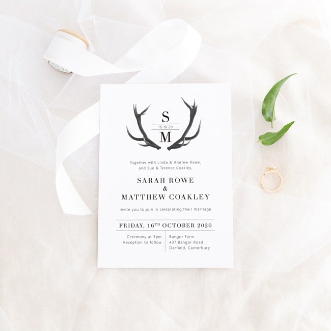 wedding invitation with deer antlers next to white ribbon